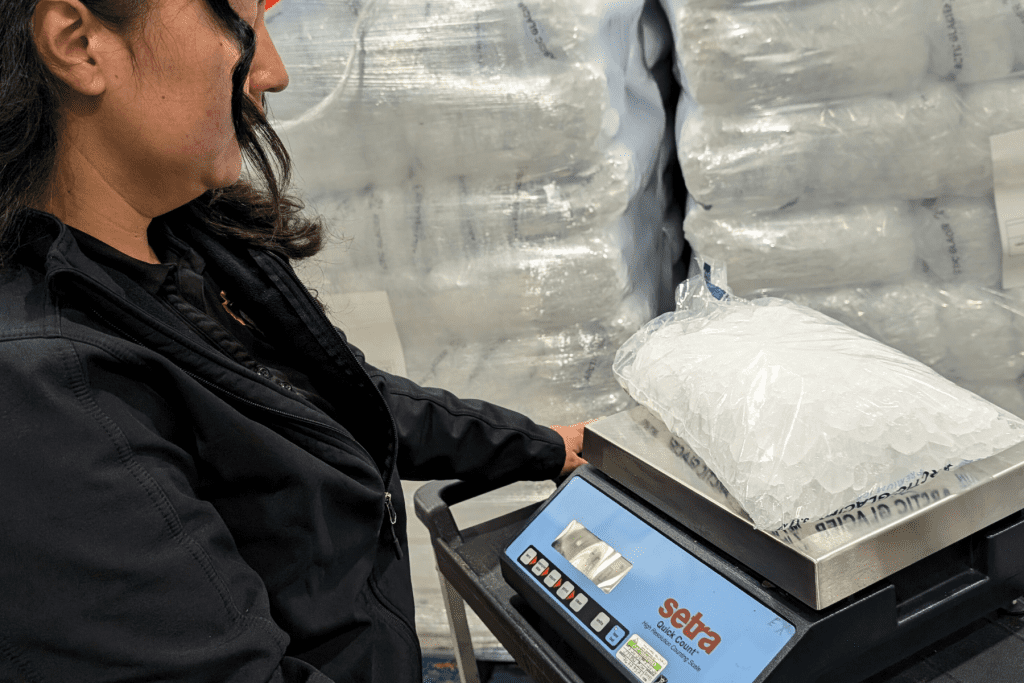 A female SBCounty Agriculture/Weights & Measures Standards Officer weighs bags of ice at a consumer retail store.