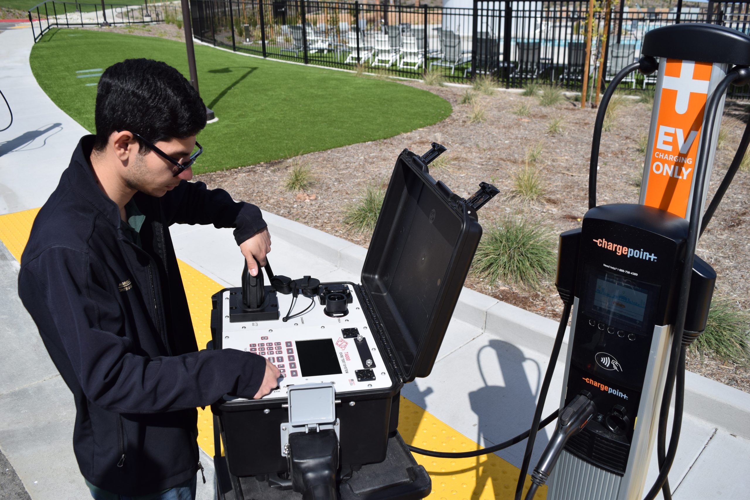 A male Agriculture/Weights & Measure Standards Officer measures an EV station with equipment.