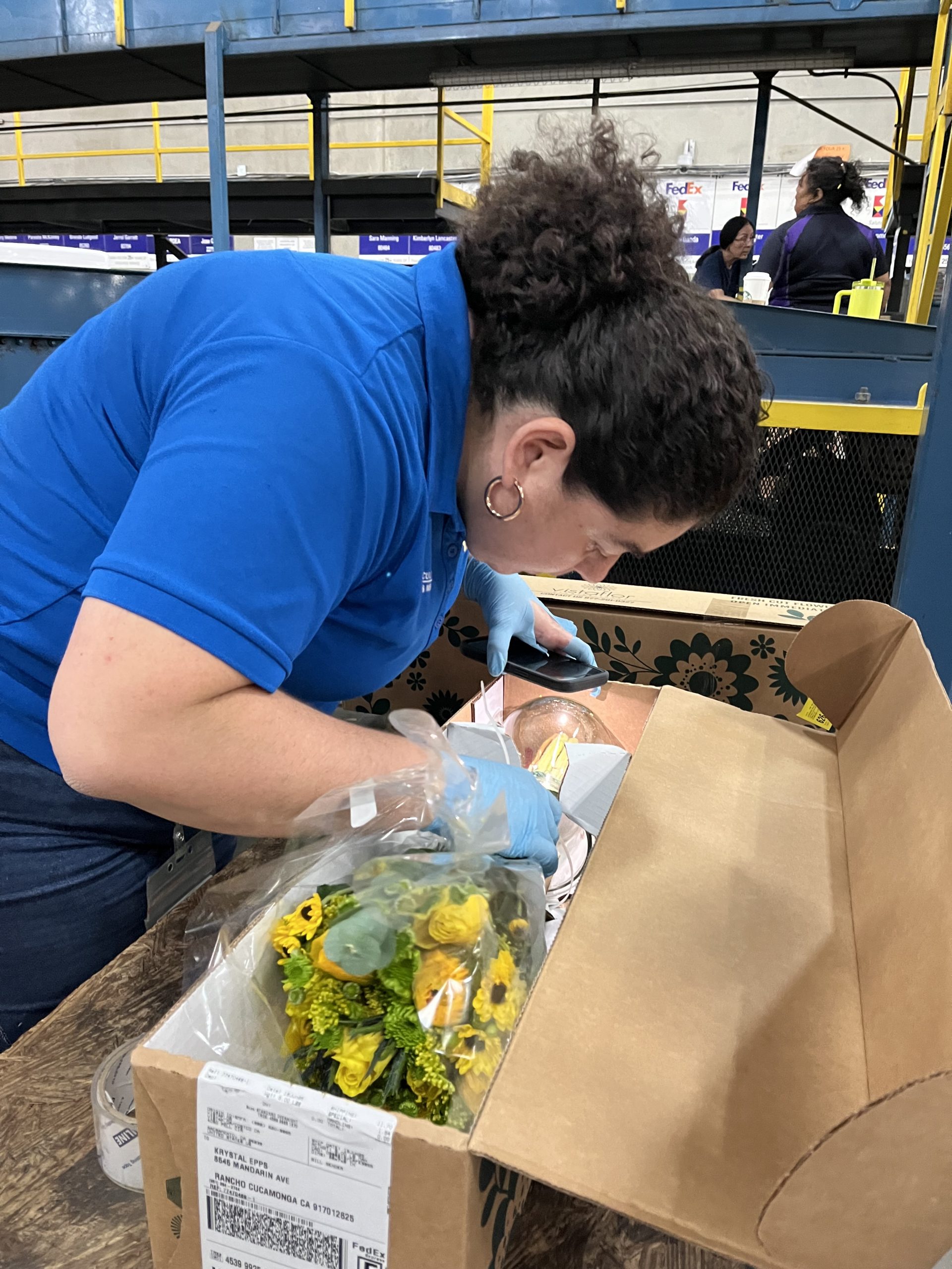 A female Agriculture/Weights & Measures Standards Officer inspects fresh cut flowers at a shipping facility.