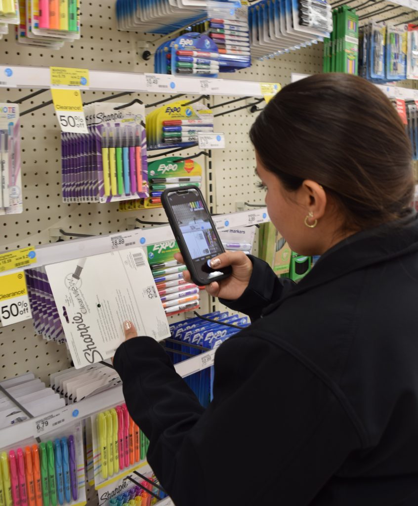 A female Agriculture/Weights & Measures Standards Officer inspects retail consumer packaging codes.