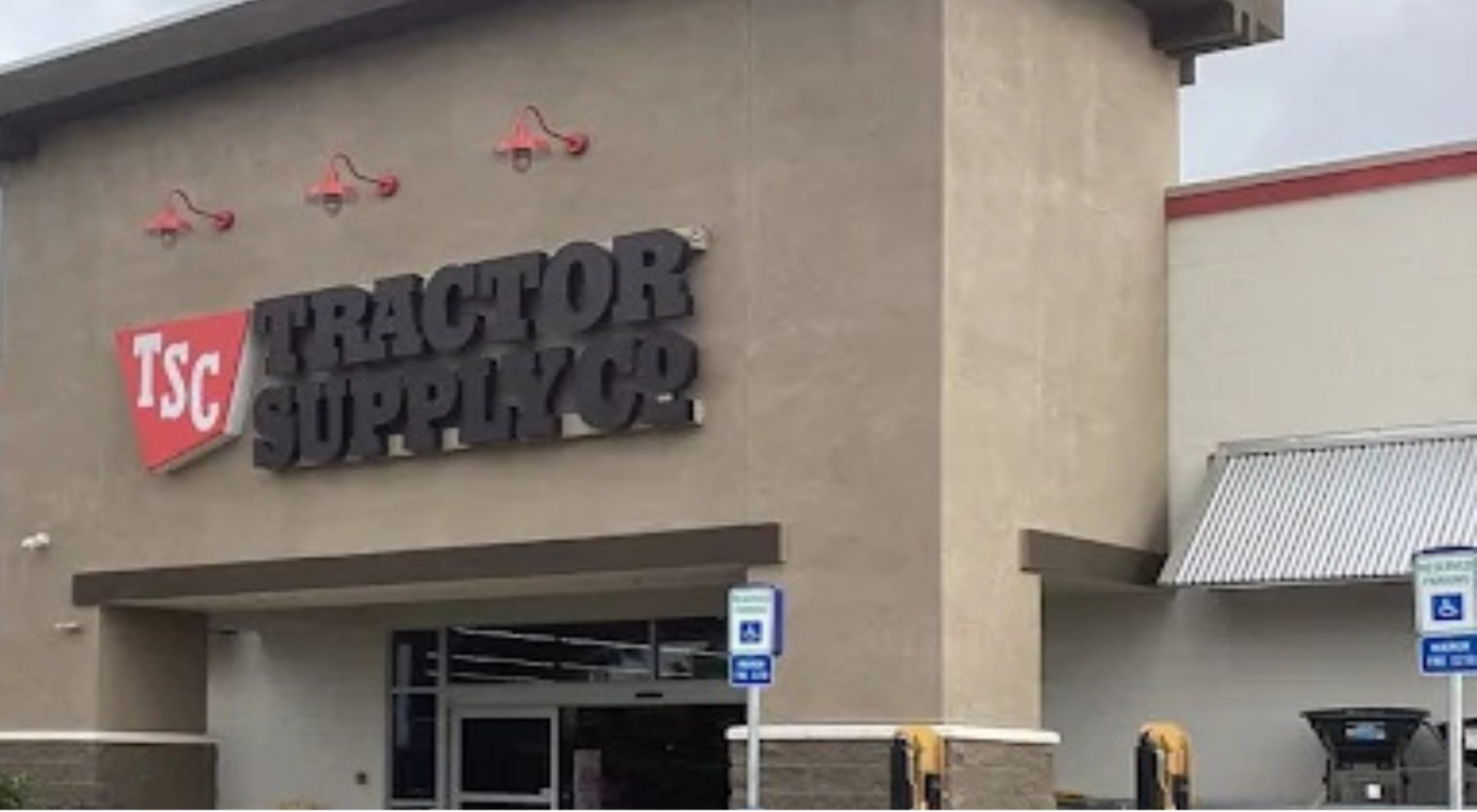 Exterior of a Tractor Supply Co. store with the company’s red and black sign above the main entrance and accessible parking signs near the storefront.